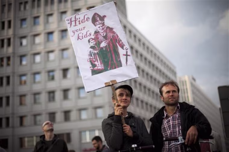 Demonstrators hold a poster reading \"Hide your kids\" as they protest against the visit of Pope Benedict in Berlin Thursday, Sept. 22, 2011.  Pope Benedict XVI is on a four-day official visit to his homeland Germany. (AP Photo/dapd,  Maja Hitij)